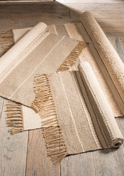 Three woven rugs with fringes on a wooden floor