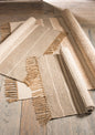 Three woven rugs with fringes on a wooden floor